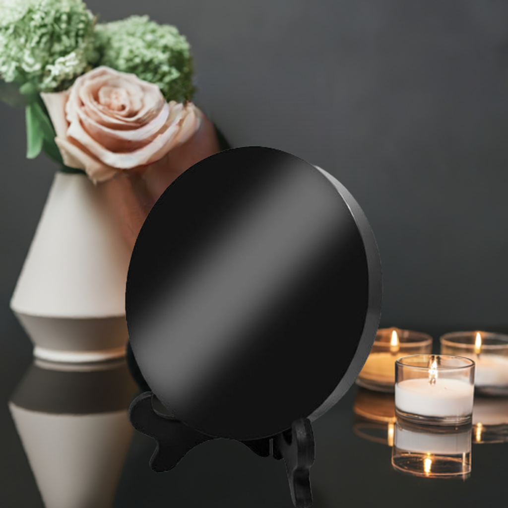 An obsidian mirror sits on a table among candles and flowers